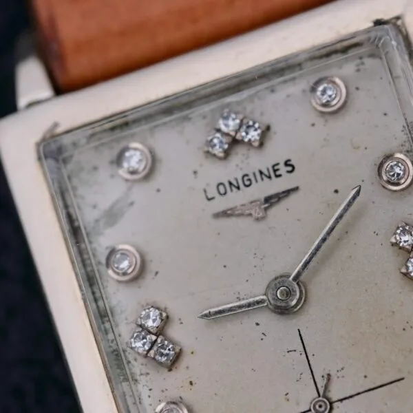 Close-up of the vintage Longines Tank 14k White Gold Diamond Dial Cal. 370, featuring a rectangular face with diamond hour markers and a single hand. Its worn, aged look enhances its timeless charm and appeal.