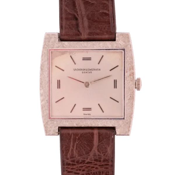The vintage Vacheron Constantin 6761 Cal 1003 watch features a minimalist rectangular dial with textured metal framing and a brown leather strap, prominently displaying the prestigious brand name on its face.