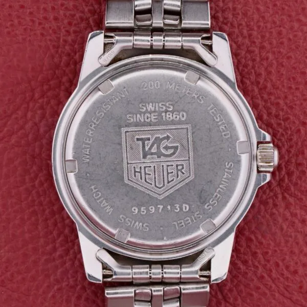The back close-up of a Tag Heuer 1500 Series watch, set on a textured red surface, displays engravings: TAG Heuer, Swiss Since 1860, and Water Resistant - Tested 200 Meters, alongside other specifications.