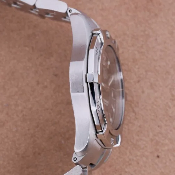 A close-up of the Tag Heuer Professional Dive watch reveals its intricate design with a metal band and round face, elegantly displayed on a light brown surface, highlighting its sophistication.