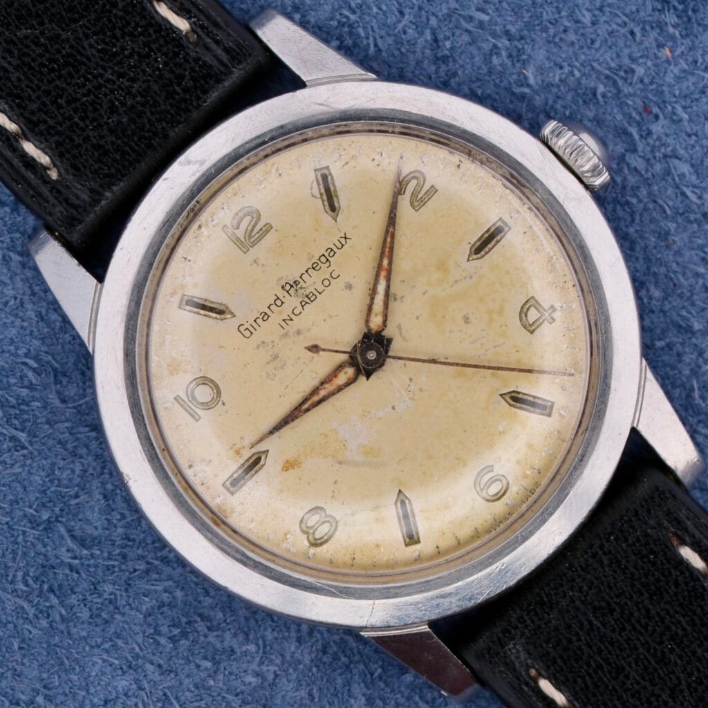 Girad Perregaux Incabloc Manual Wind watch with a worn cream dial, silver case, and classic black leather strap.