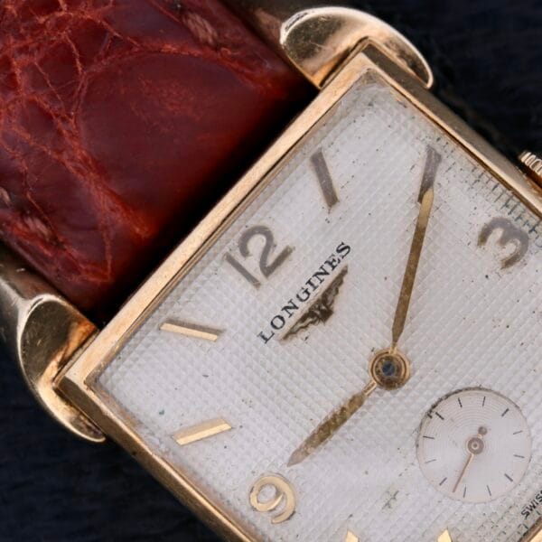 The Longines Franklin Square Waffle Dial Cal 23Z watch features a square textured white dial with gold-toned hour markers and hands, a small seconds sub-dial, and a brown leather strap that completes its timeless elegance.