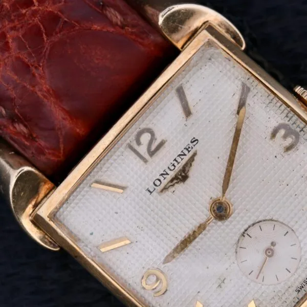 The Longines Franklin Square Waffle Dial Cal 23Z watch features a square textured white dial with gold-toned hour markers and hands, a small seconds sub-dial, and a brown leather strap that completes its timeless elegance.