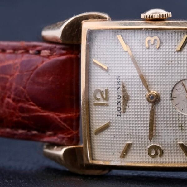 The Longines Franklin Square Waffle Dial Cal 23Z features a vintage square textured silver dial, gold-tone numerals and hands, the brand name on the left side, and a visible-stitched leather strap. Its elegantly set to show the time as 10:11.