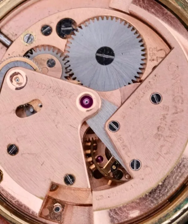 Close-up of the Omega Automatic Bumper watch movement, showcasing intricate mechanical gears and components in a rose gold tone, with Omega Watch engraved on the surface.