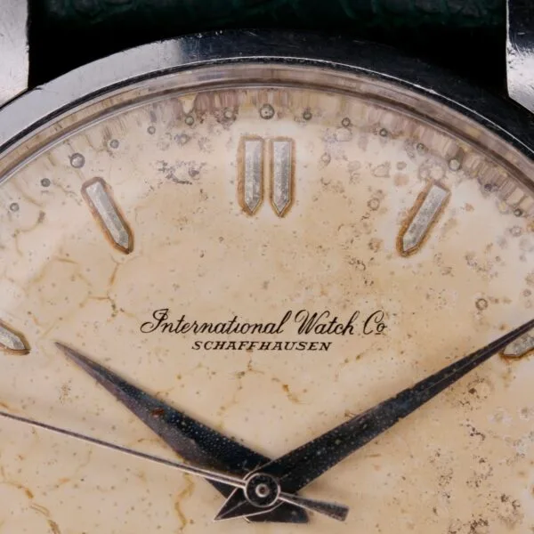 Close-up of an IWC Caltrava Jumbo Cal. 89 Stainless Steel wristwatch face with patina, featuring silver hour and minute hands, triangular hour markers, and the text International Watch Co Schaffhausen, enhancing its classic and vintage look.