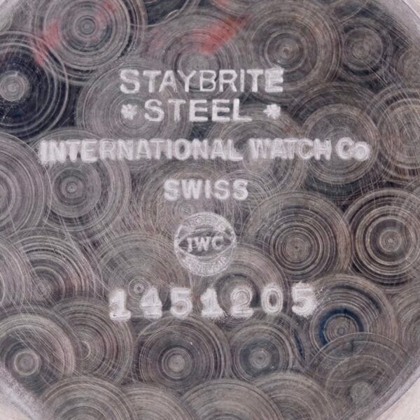 Close-up of the IWC Caltrava Jumbo Cal. 89 Stainless Steel watch case back with STAYBRITE STEEL, INTERNATIONAL WATCH CO, SWISS, featuring its logo and serial number 1451205 on a polished circular background.