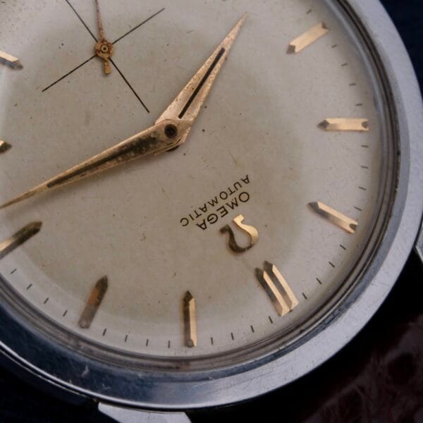 Close-up of the Omega Automatic Bumper Cal 344 Stainless Steel watch, highlighting a cream dial with gold hour markers and hands. Omega and Automatic are elegantly displayed beneath the hands, featuring an automatic movement.