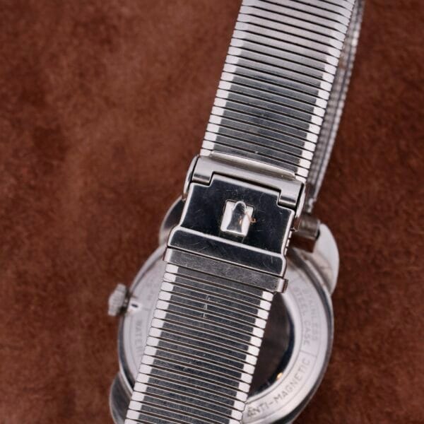 A close-up of the Bulova Seabee Charcoal Waffle Dial watch with a ribbed band on a brown textured surface, featuring its signature Charcoal Waffle Dial, engraved back, and visible strap clasp.