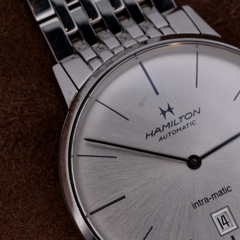 The Hamilton Intramatic Date Stainless Steel H38455151 is a sophisticated Swiss-made watch featuring the reliable 2892-2 automatic movement. It boasts a 41mm stainless steel case with a sleek silver dial, minimalist hour markers, and a discreet date function at 6 o'clock. The original 22mm stainless steel bracelet offers both comfort and durability, making it ideal for everyday wear and special occasions. This timepiece combines high-quality materials, expert craftsmanship, and timeless design, making it a distinguished addition to any watch collection.