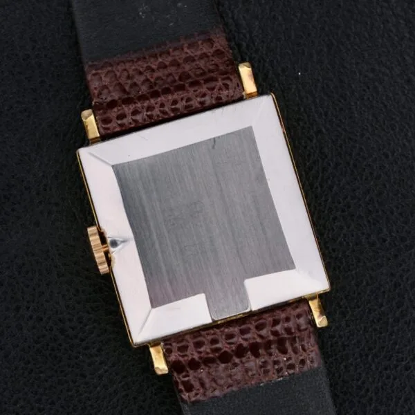 An Omega Deville Turler Dial square metal case wristwatch with a textured brown leather strap is elegantly displayed on a dark leather surface. The brushed-finish case back and gold-colored crown enhance the watchs refined craftsmanship.