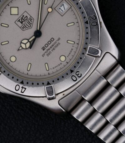 The Tag Heuer Professional 2000 Ref 962.206 is a Swiss-made quartz watch from the 1990s, featuring a 38mm stainless steel case and original stainless steel bracelet. Its gray dial with silver-toned hands and indices ensures readability, while the central seconds hand, hack second function, and rotating bezel add precision and functionality. With a 20mm lug width, it offers a comfortable fit and a minimalist, uncluttered design, making it a versatile and stylish choice for both daily wear and special occasions.