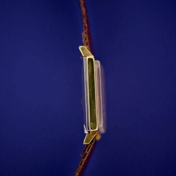 Side view of an Omega Deville 111.071 Turler Dial Square Case wristwatch with a brown leather strap and gold accents, set against a blue background.