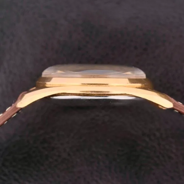 Side view of a Vulcain Cricket 17 Jewels watch face, featuring a gold-toned case and textured black background.