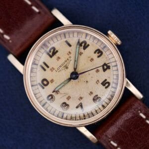 Longines Military 24 Hour Dial 12L wristwatch with a brown leather strap and an aged cream dial, showcased on a blue background.