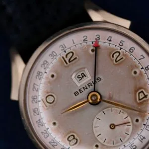 A close-up of the Benrus Day/Date Pointer watch shows an aged white dial with Arabic numerals at 2, 4, 8, and 10. The date window reads SA for Saturday, complemented by a small seconds sub-dial at the 6 oclock position.