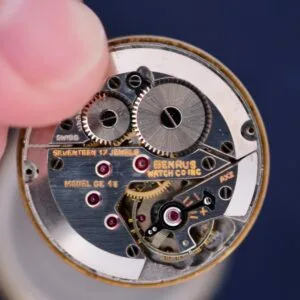 A close-up shows a vintage Benrus Day/Date Pointer watch movement, featuring an intricate mechanism with gears marked SWISS, BENRUS WATCH CO. INC., SEVENTEEN 17 JEWELS, and MODEL GE AE.