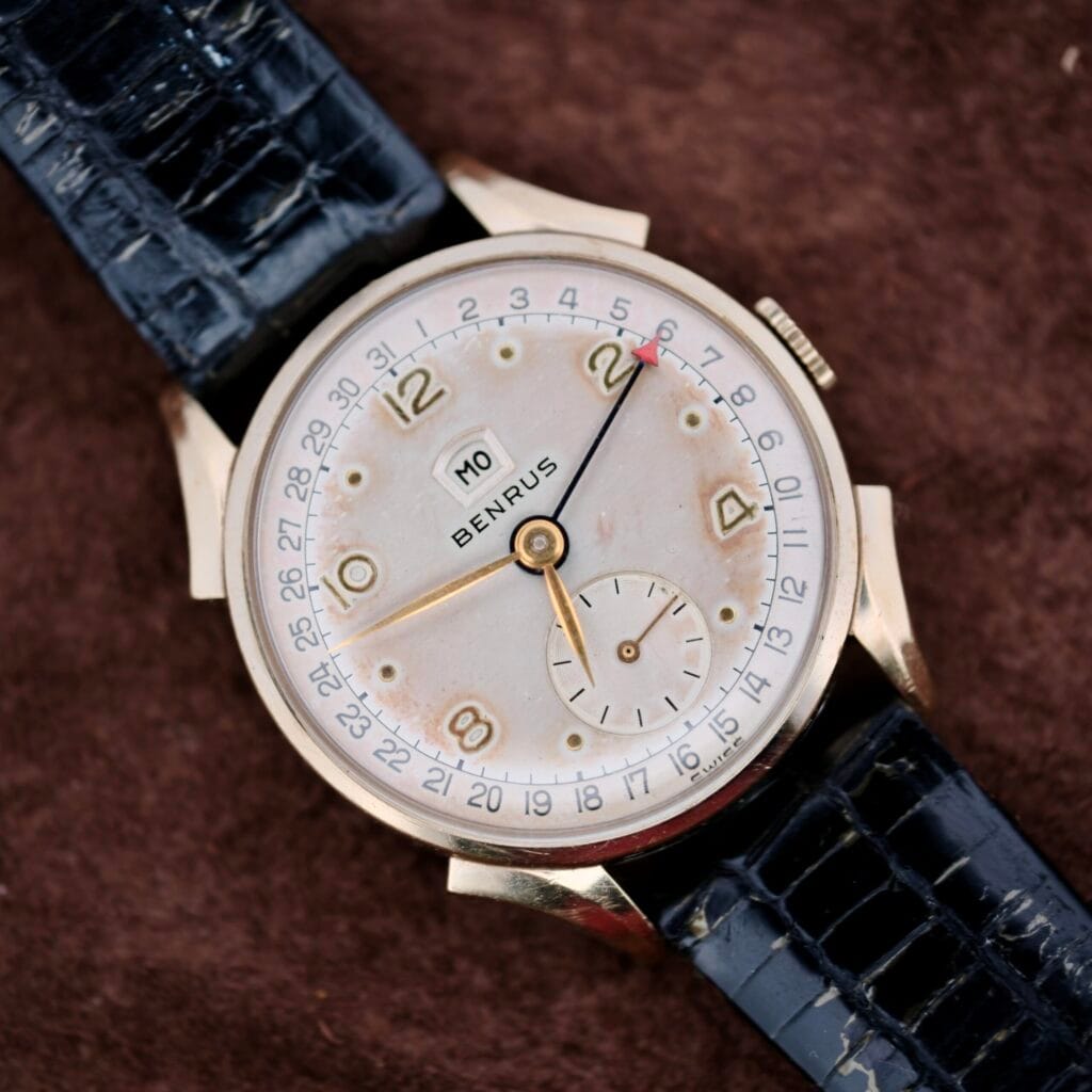 The Benrus Day/Date Pointer features a black leather band and gold numerals on a brown textured dial—an ideal vintage wristwatch for collectors seeking timeless style.