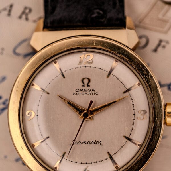 Close-up of an Omega Seamaster Automatic Ref. 14350-2 Bull Horn Lugs vintage gold wristwatch with a white dial and leather strap.