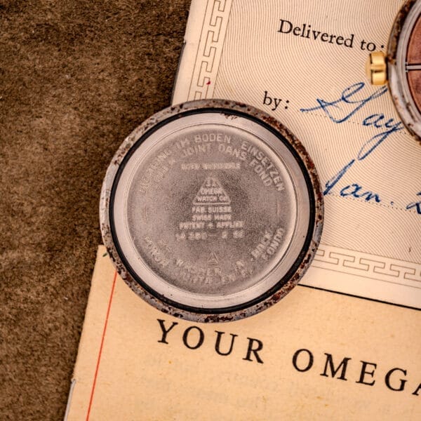 Close-up of an open Omega Seamaster Automatic Ref. 14350-2 Bull Horn Lugs case back with engraved markings, resting on vintage papers.