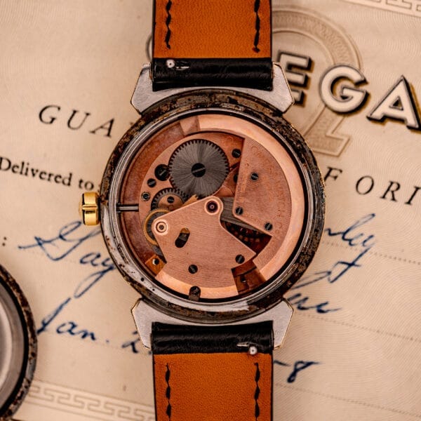 A close-up of the Omega Seamaster Automatic Ref. 14350-2 Bull Horn Lugs’ exposed mechanical movement, displayed on vintage documents.