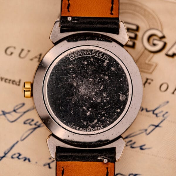 Close-up of the scratched back of an Omega Seamaster Automatic Ref. 14350-2 Bull Horn Lugs resting on handwritten papers.