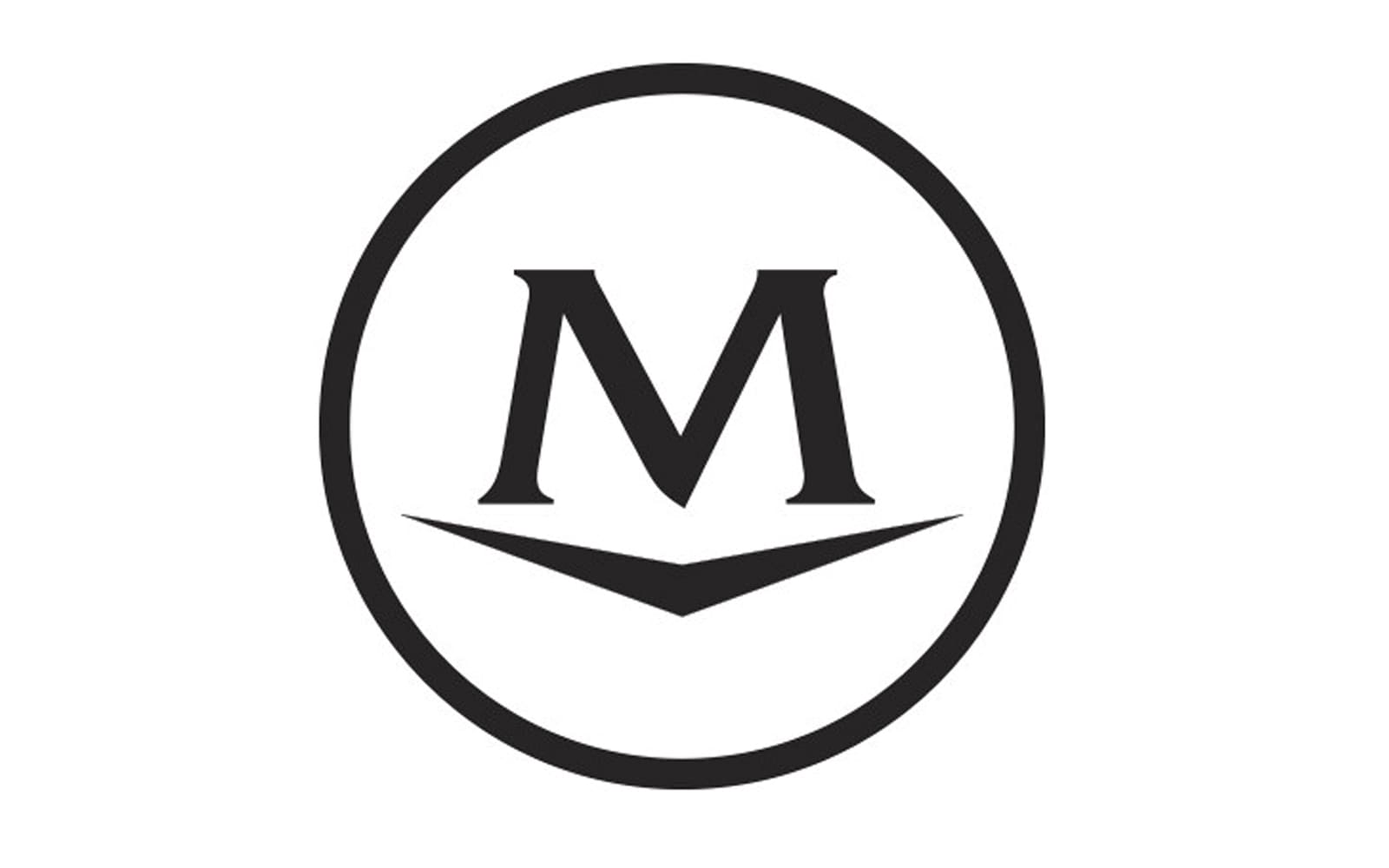 A bold capital letter M is centered inside a black circular outline. Below the M is a stylized V shape, possibly resembling an open book or check mark. The design is simple and monochromatic on a white background.