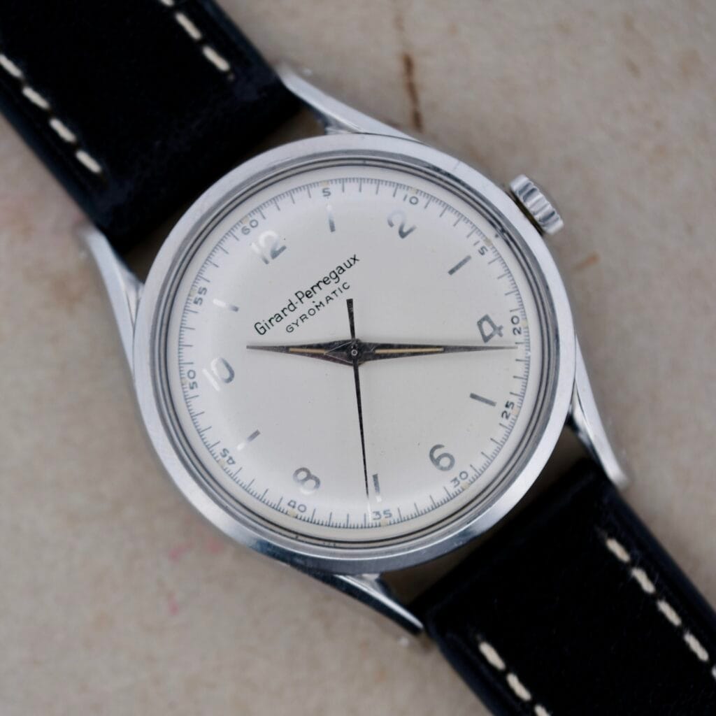 A vintage Girard Perregaux Gyromatic 6169 Caliber 47 wristwatch with a classic white dial and elegant black leather strap.