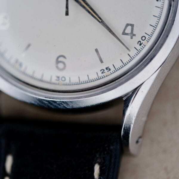 The close-up reveals the elegant face of a Girard Perregaux Gyromatic 6169 Caliber 47, highlighting numbers 2, 3, and 4. Sleek black hands glide smoothly with minute markers accentuating the design. A silver case and a partially visible black leather strap complete this timeless piece.