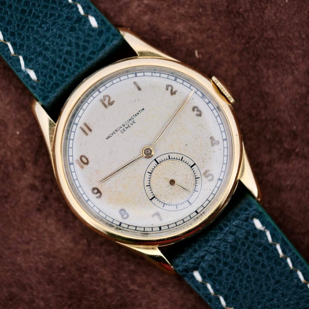 A 1940s Vacheron Constantin Caltrava V453 gold wristwatch featuring a white dial and blue leather strap, displaying the time as 7:22.