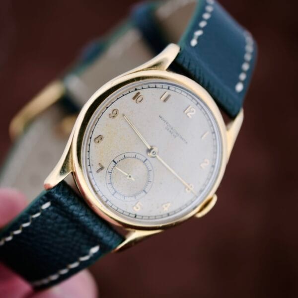 The 1940s Vacheron Constantin Caltrava V453 is a timeless vintage wristwatch with a gold case and black leather strap. It features a round white dial, subtle gold hour markers and hands, and an elegantly placed small second subdial above the 6 oclock position.
