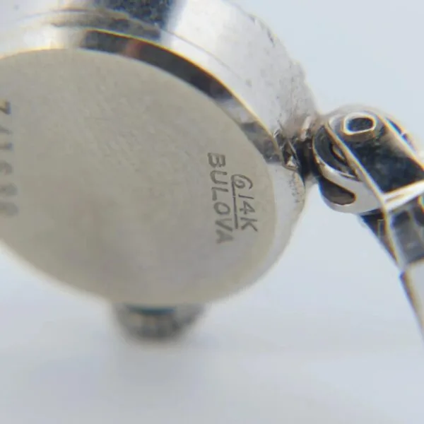 Close-up of a 1950s Bulova 14K Ladies White Gold & Diamond Watchs back, displaying Bulova and 14K. The case has a metallic finish, with the strap attachment visible on the right.