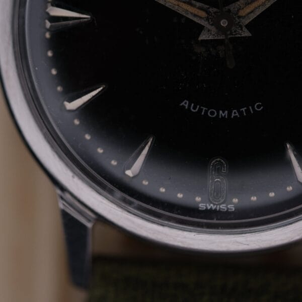 Close-up of a 1960 Hamilton Thin-o-Matic T-501 Micro-Rotor wristwatch, featuring silver hour markers on a dark face. The numbers 6 and SWISS appear at the bottom, with AUTOMATIC printed on the right side of the dial.