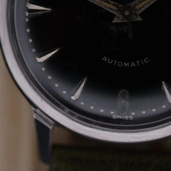 Close-up of a 1960 Hamilton Thin-o-Matic T-501 Micro-Rotor wristwatch, featuring silver hour markers on a dark face. The numbers 6 and SWISS appear at the bottom, with AUTOMATIC printed on the right side of the dial.