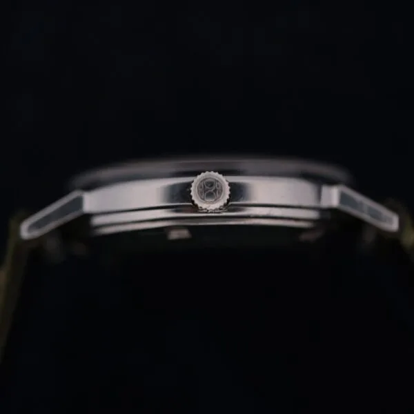 Side view of the 1960 Hamilton Thin-o-Matic T-501 Micro-Rotor in a dark setting, highlighting its metal case, lugs, and gear-patterned crown.