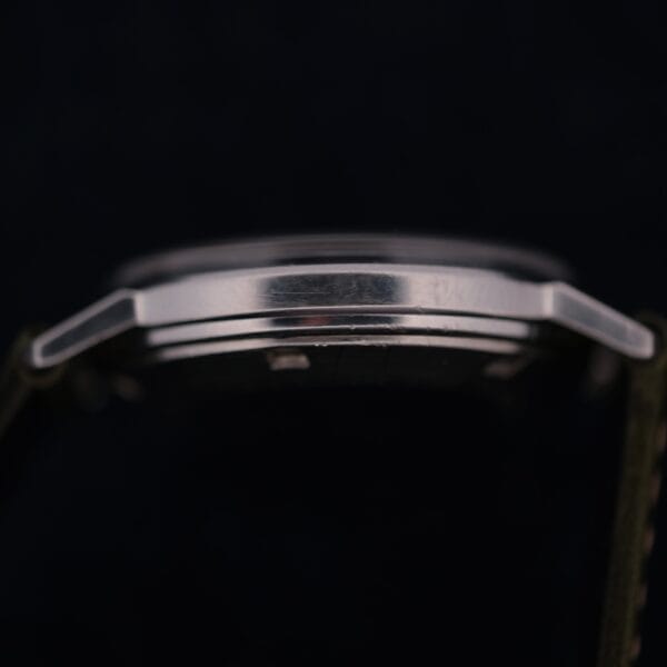 A close-up side view of the 1960 Hamilton Thin-o-Matic T-501 Micro-Rotor’s silver case with a metallic finish, highlighting the case edge and part of the strap against a dark background.