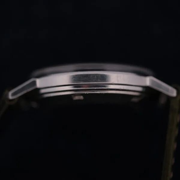 A close-up side view of the 1960 Hamilton Thin-o-Matic T-501 Micro-Rotor’s silver case with a metallic finish, highlighting the case edge and part of the strap against a dark background.