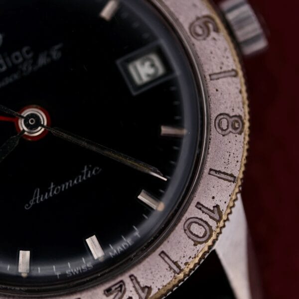 Close-up of a 1960s Zodiac Aerospace GMT Automatic Date wristwatch, displaying the brand name, Automatic, a date window showing 13, an engraved bezel, and the time at about 10:08.