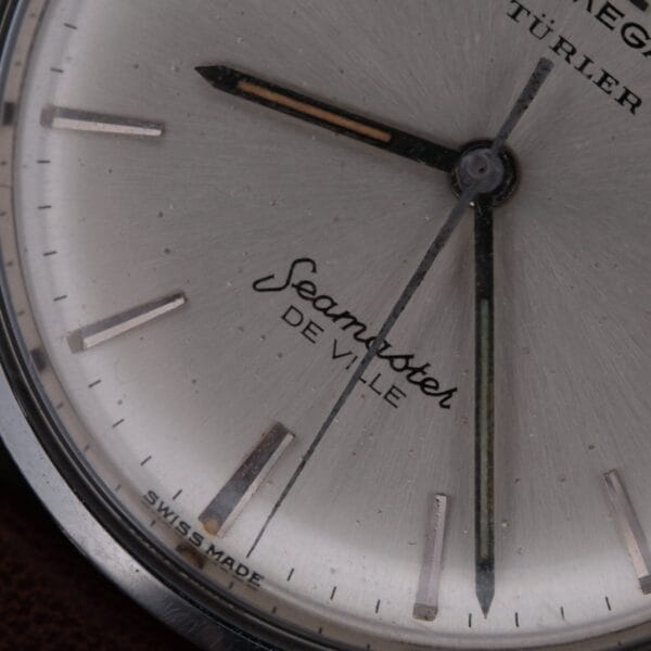 Close-up of a 1963 Omega Seamaster Deville Türler Dial Ref. 135.010, featuring “OMEGA,” “TURLER,” “Seamaster DE VILLE,” and “SWISS MADE” on a light dial with silver hour markers and hands.