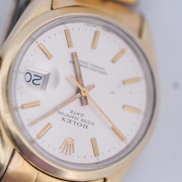 Close-up of a 1974 Rolex Oyster Perpetual Date Ref. 1550 with a gold and silver band, round white face, gold hour markers, hands, date window at 20, and visible brand name and model text on the dial.