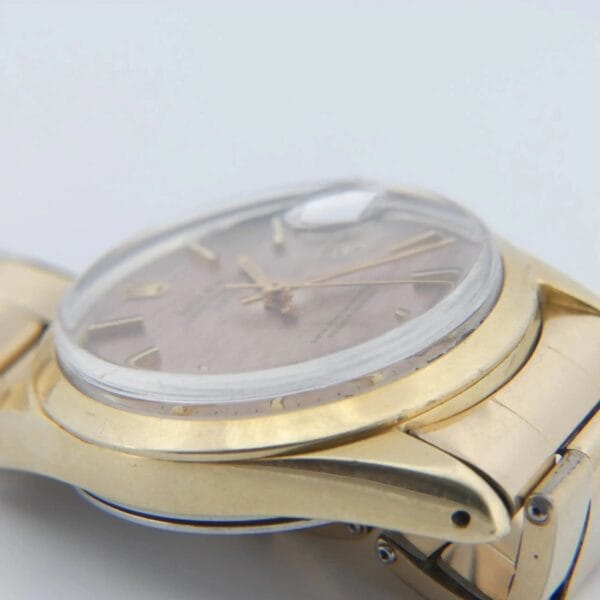 Close-up of a 1978 Rolex 1550 Oyster Perpetual Date featuring its stainless steel and gold bracelet. The watch has a domed crystal, beige dial with gold hour markers, two hands, and showcases a smooth, polished finish on its side.