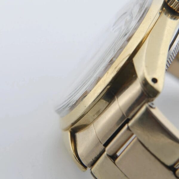 Close-up of the Rolex 1978 Oyster Perpetual Date 1550 in a gleaming 14k gold shell, showcasing its metallic case and bracelet. The watch face is partly visible, with light reflecting off the glass, highlighting intricate craftsmanship.