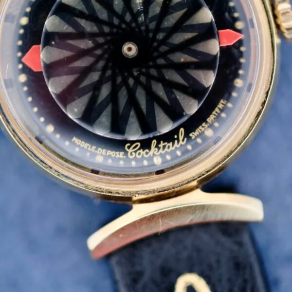 Close-up of the Ernest Borel Kaleidoscope Cocktail Black Dial watch with a captivating black and white pattern. The gold case is paired with a blue leather strap, while Cocktail, Modele Depose, and Swiss Patent are elegantly marked on the dial.