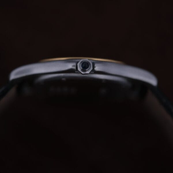 Close-up side view of the Cartier Cougar Gents Date Ref. 187904, focusing on its polished metallic crown against a dark background.