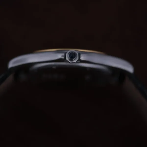 Close-up side view of the Cartier Cougar Gents Date Ref. 187904, focusing on its polished metallic crown against a dark background.