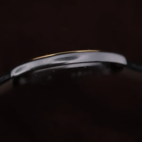 Close-up side profile of the Cartier Cougar Gents Date Ref. 187904 case against a dark background, highlighting its thin metal edge with subtle reflections and gently curved shape.