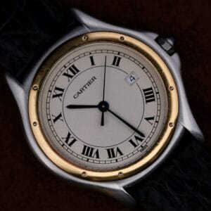 Cartier Cougar Gents Date Ref. 187904 wristwatch featuring classic Roman numerals, gold bezel, black leather strap, and date window positioned at 4 oclock.