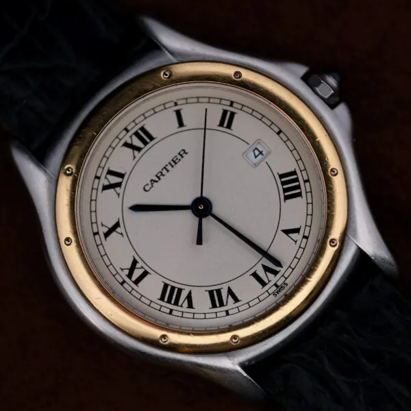 A close-up of the Cartier Cougar Gents Date Ref. 187904 wristwatch with a round white dial, black Roman numerals, gold bezel, black leather strap, and a date window showing 4. The time displayed is approximately 8:19:37.