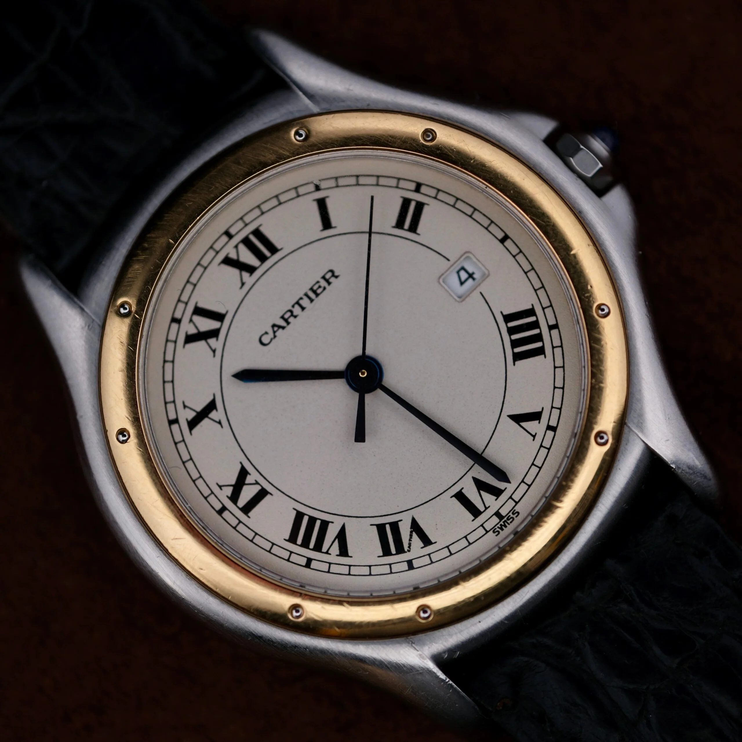 Cartier Cougar Gents Date Ref. 187904 wristwatch featuring classic Roman numerals, gold bezel, black leather strap, and date window positioned at 4 oclock.