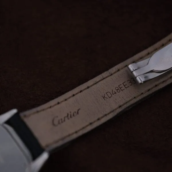 A close-up of a leather watch strap for the Cartier Cougar Gents Date Ref. 187904, with Cartier and the code KD48EE33 stamped underneath, displayed against a dark brown background.